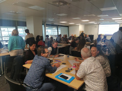 Participants from learning session one of the national rehabilitation collaborative sitting at tables around a room working together and talking.